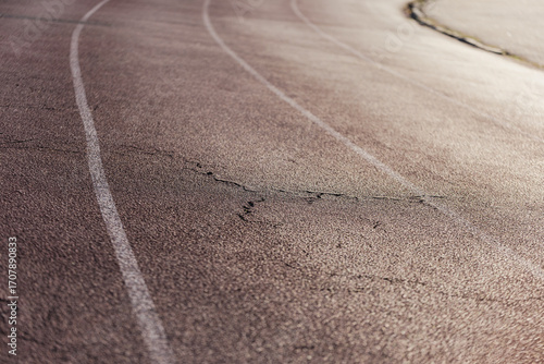 Closeup of rubber surface of stadium running track - old cracks on athlete path