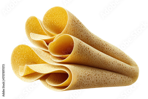 Close-up of rolled golden injera bread with bubble texture on black background, cut out