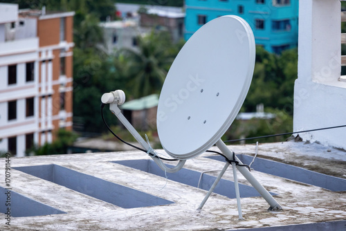 Close-up of a satellite antenna dish on the roof of a residential house in Bangladesh, highlighting the technology used for television access.