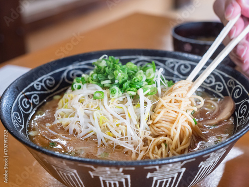 ネギともやしたっぷりのとんこつ醤油ラーメン。麺を箸あげしてる様子。