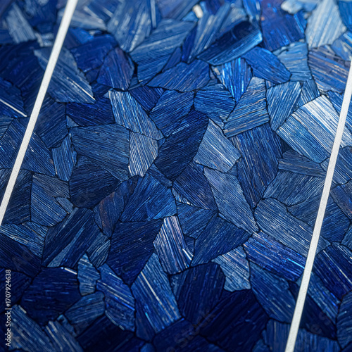 This close-up photo shows the intricate texture of a blue polycrystalline solar panel. The crystalline pattern glistens with reflected light, representing modern renewable energy technology and the mo