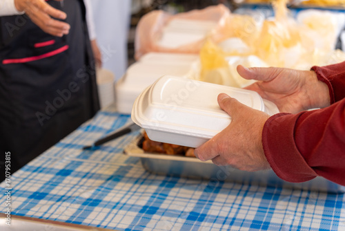 Hands exchanging takeout container at outdoor cafe.