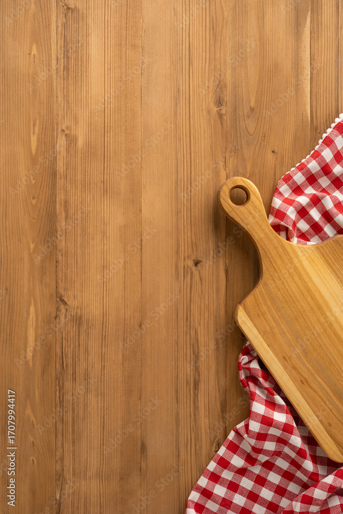 Obraz premium Vertical view of wooden countertop showing a cutting board and red-checkered tablecloth. Associated with Thanksgiving day celebration and harvest