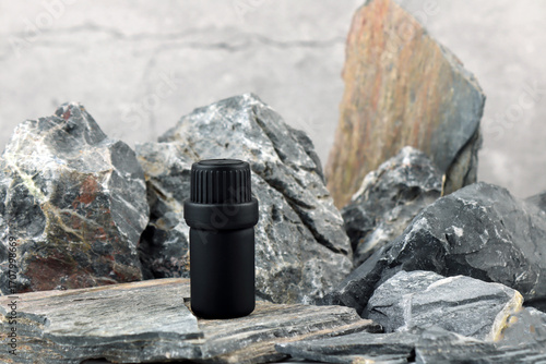 black color essential oil bottle on stone table with stones and rocks in luxury spa for create nice smell scent ambient in massage room for customer to relax fresh cozy feeling with many natural oil