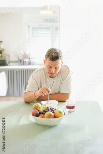 Man Enjoying Organic Cereal in a Bright Kitchen.
