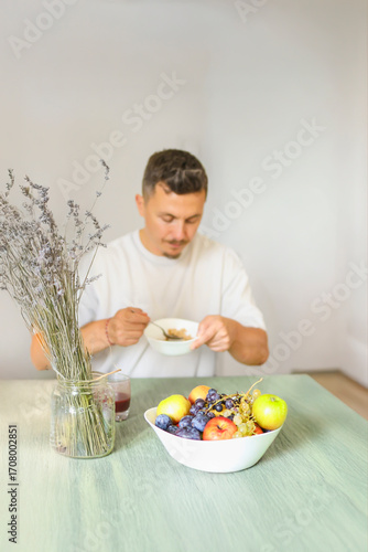 Caucasian Man in His 30s Eating Muesli at a Dining Table During Morning Routine.
