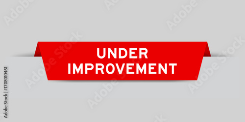 Red color inserted label with word under improvement on gray background