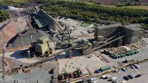 Aerial drone view of huge quarry mining operational facility, extracting rare earth minerals, heavy plant machinery and industrial conveyor belts in Coalville England UK sunny 