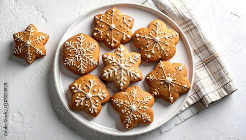 Gingerbread cookies with white icing on a white plate and a checkered napkin.