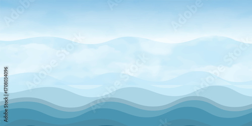 Blue sea waves with a misty mountain landscape at sunrise and a sky full of clouds