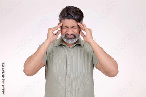 Indian man suffering from headache desperate, stressed pain and migraine. Hands on head closing eyes to relieve pain isolated on white studio background