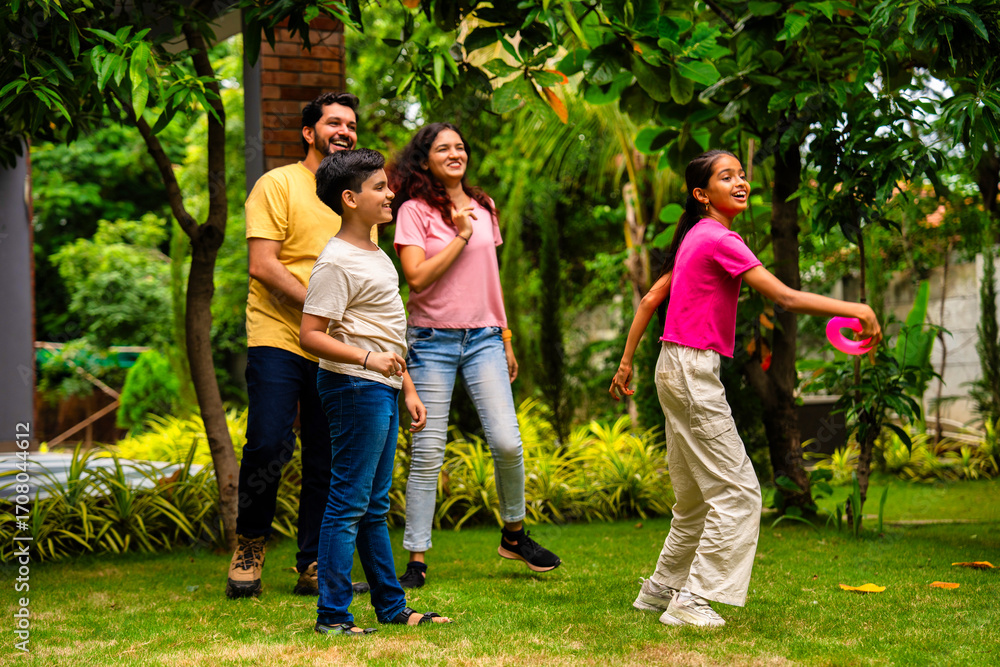 Fototapeta premium Indian family playing Tennikoit ring game outdoors, enjoying quality leisure time together