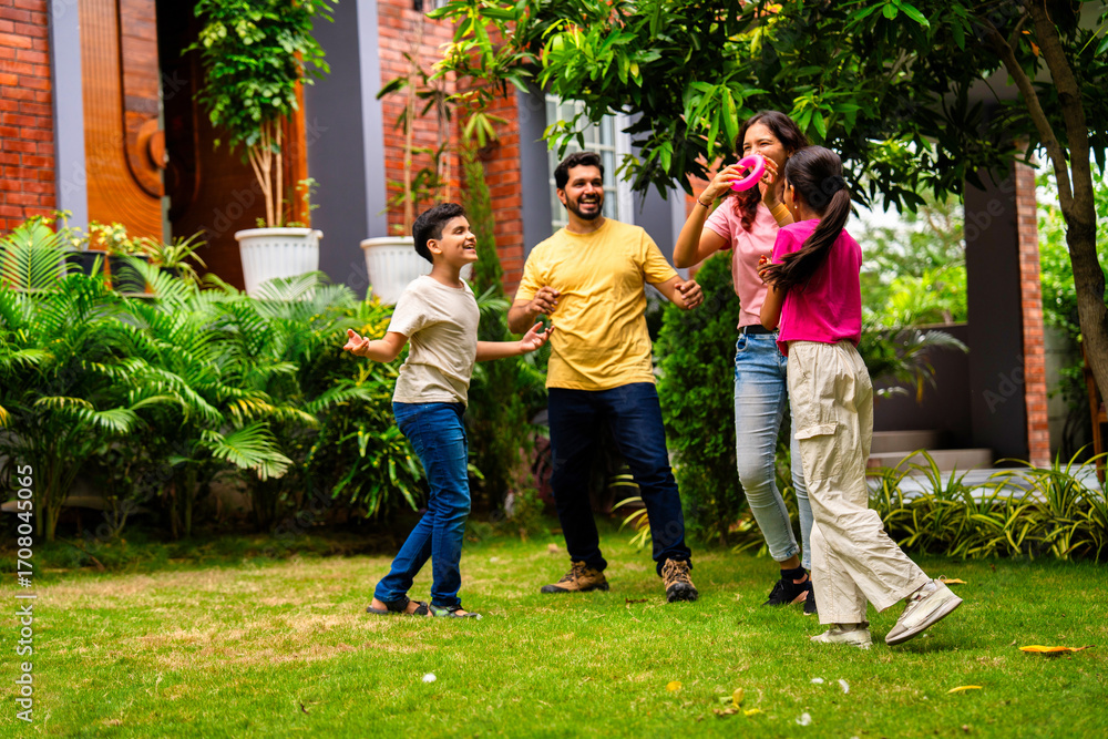Fototapeta premium Indian family playing Tennikoit ring game outdoors, enjoying quality leisure time together
