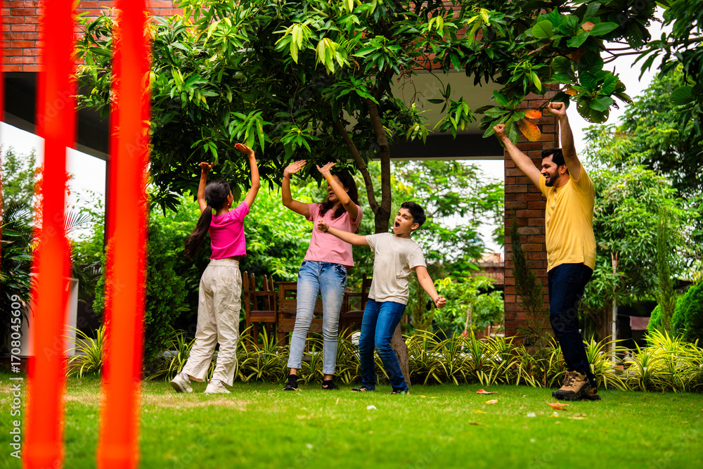 Fototapeta premium Indian family plays cricket bowling at home, enjoying weekend fun with kids in garden