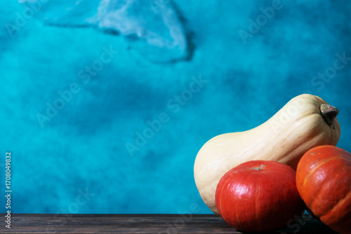 Various types of pumpkins on a wooden surface against a blue background