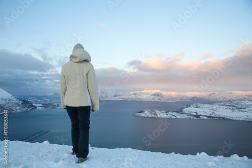 Donna con vestiti invernali sul punto panoramico nell'Artico a nord della Norvegia. Belvedere a Sørstraumen, isole di Spildra e Skorpa. Fiordo Kvaenangen.