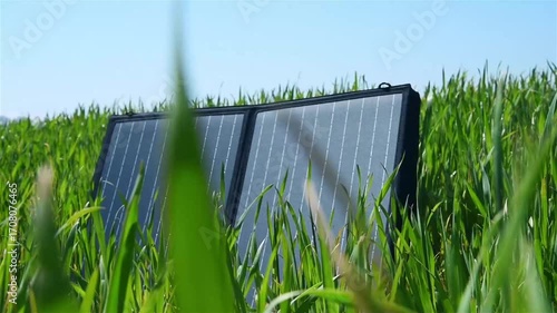 Portable solar panel on green grass. Alternative energy and clean technology concept.