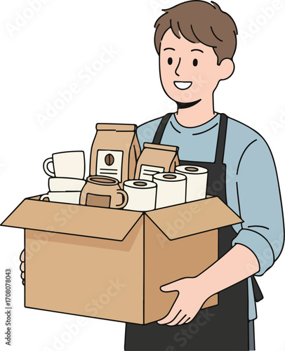 A smiling person wearing a blue shirt and black apron holds a cardboard box full of supplies. The box contains several items, including bags of what appears to be coffee beans, mugs, and rolls of toil