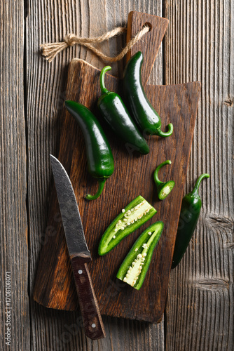 Black jalapeno with knife on rustic wooden cutting board close up. Green mexican jalapeno hot peppers