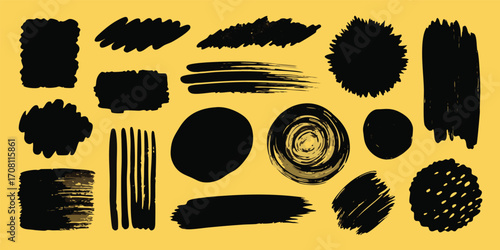 Collection of grunge paint brush strokes and splatters in various shapes for artistic design elements and creative projects on a yellow background