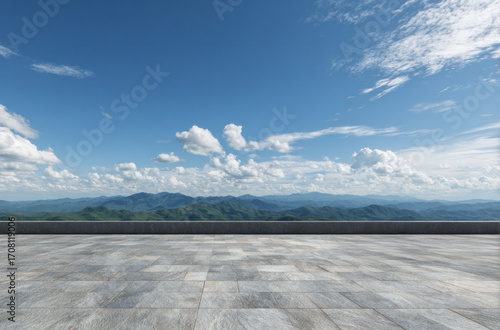 A vast open square with a beautiful mountain landscape under a clear blue sky with scattered clouds.