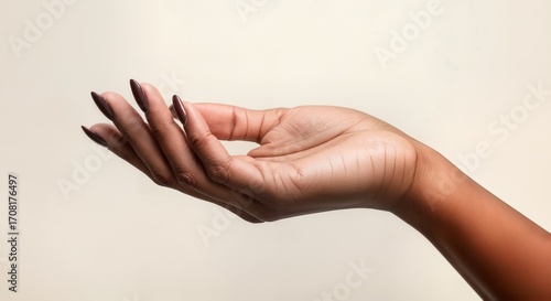 Elegant female hand with dark brown manicure on beige background, beauty salon concept
