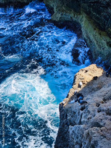 Mineralrich spring, vibrant colors, unique formations. Rocky cliff, overlooking a vast expanse of vibrant blue ocean water below. Water and rocks. Aerial view of coastline cliff. Sea and rocks.