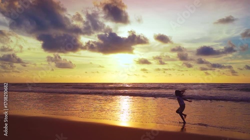 Young girl running on beach sandy shore at sunset Amazing light sunset or sunrise sky watching sea Happiness travel and bliss concept video