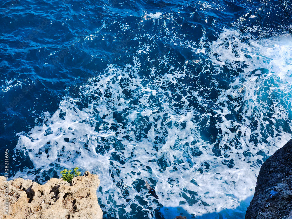 Fototapeta premium Aerial view of wave pattern. Beautiful abstract background of blue water with waves and splashes. Aerial view of the ocean water surface and waves. Blue water of ocean. Blue sea and a moving.