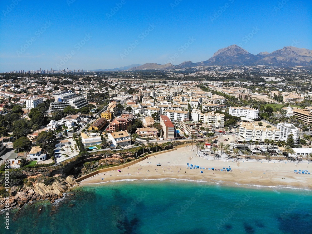 Fototapeta premium Beach town El Albir in Alfaz del Pi municipality of Alicante Province, Valencian Community in Spain. Costa Blanca region holiday town. Drone point of view in April.