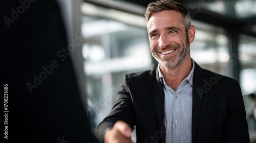 Smiling Businessman Shaking Hands in a Modern Office Setting, Highlighting Professionalism, Collaboration, and Cheerful Workplace, Concept of Corporate Partnerships, Leadership, and Business Relations