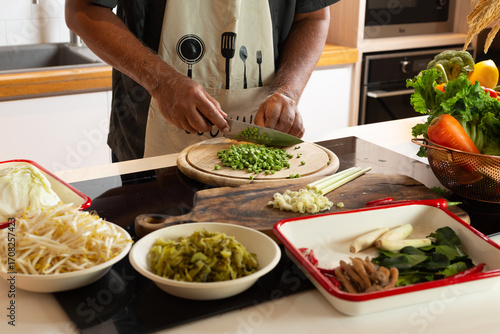 Man Cutting Long Beans with Fresh Vegetables on Kitchen Counter