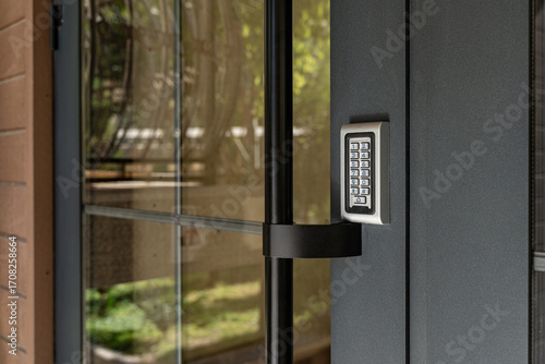 Closeup of modern door with electronic keypad access control system, secure building entrance technology.