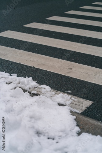 Wallpaper Mural Snow partly covering crosswalk lines on dark asphalt in urban winter scene Torontodigital.ca