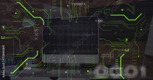 Showing flat-screen monitor with code, neon circuit graphics and binary digits on office desk