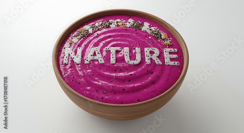 Vibrant pink smoothie bowl artfully decorated with seeds and nuts spelling NATURE, a healthy delight.