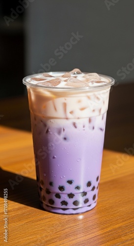 A refreshing ube purple yam dessert drink in a clear cup. The drink features layers of purple and cream colors with tapioca pearls at the bottom.