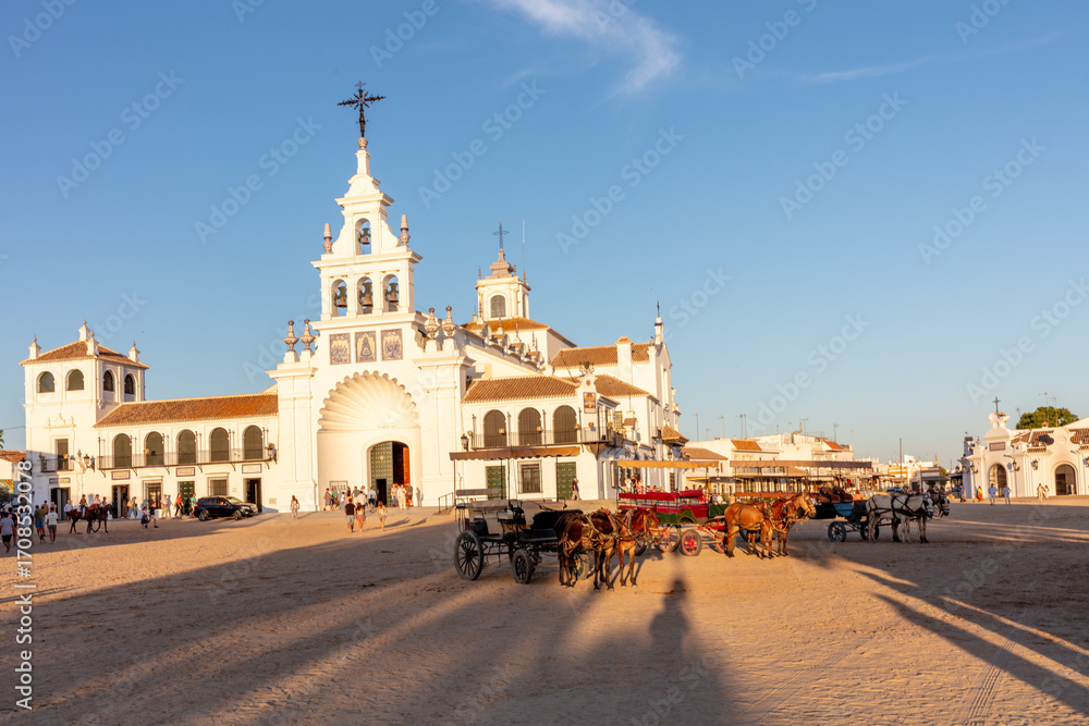 Naklejka premium El Rocio, Sevilla, Andalusia, Spain. 28 August 2025. Horses with a cart in front of the Hermitage of El Rocio