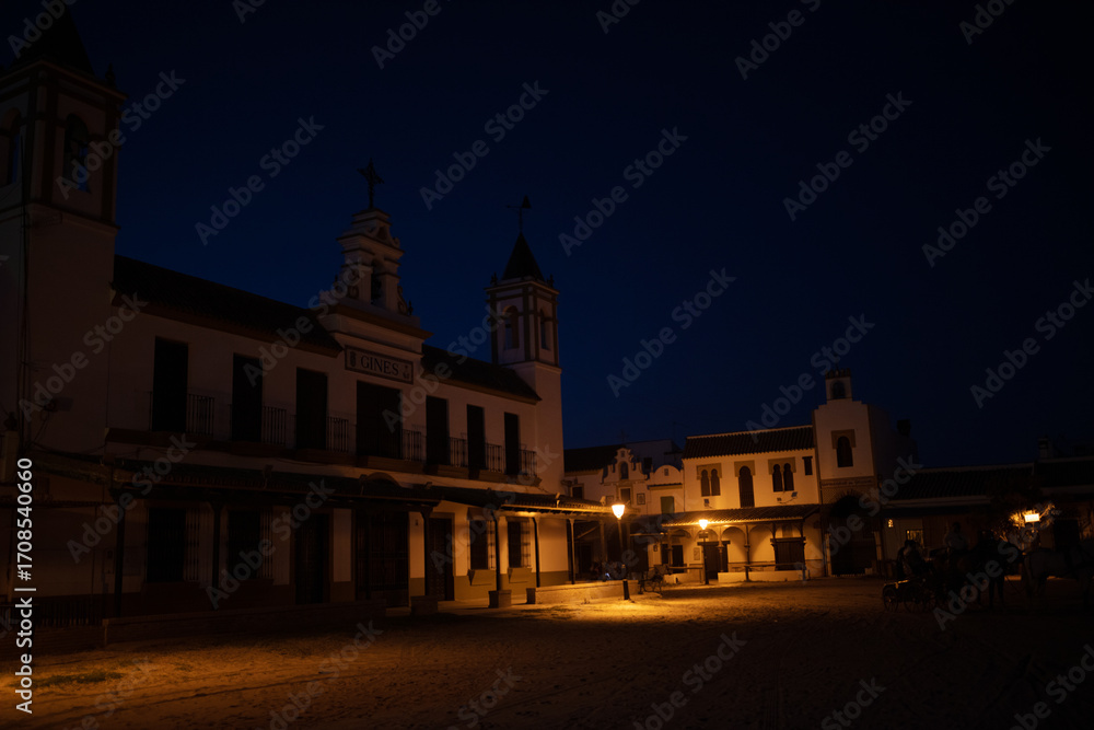 Fototapeta premium El Rocio, Sevilla, Andalusia, Spain. 28 August 2025. Hermandad house illuminated at dusk
