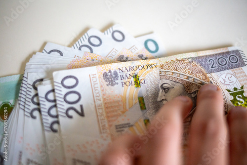 Photos Fingers touching stack of 200 Polish złoty notes