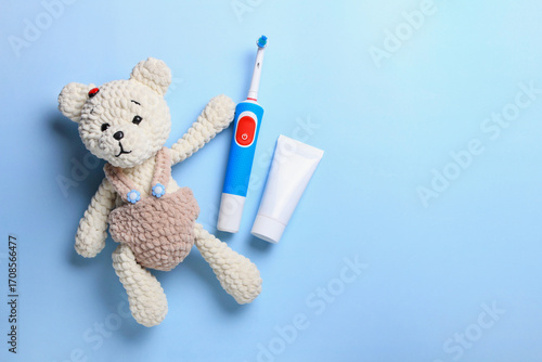Soft teddy bear with toothbrush and toothpaste on a blue background for child dental care