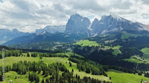 Forest patches and open grasslands under cloud shadows, Langkofel skyline, aerial view. Dolomite highlands with summer vegetation
