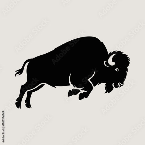 Silhouette of a charging bison in profile against a light background
