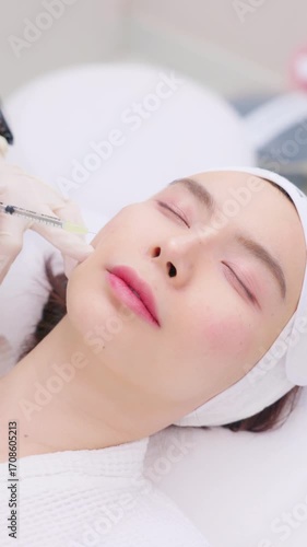 A close-up of a young Asian woman receiving a Botox or dermal filler injection in her face from a professional. Concept for beauty clinics, dermatology, and anti-aging treatments.