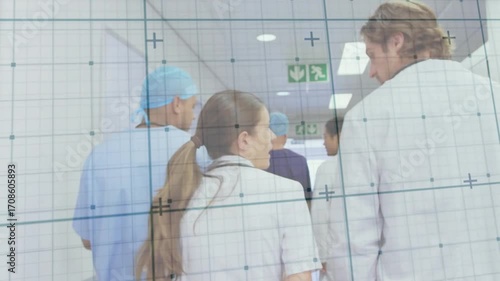 Medical team after surgery briefing walking hospital corridor wearing stethoscope toward OR door