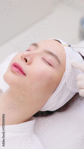 A close-up of a young Asian woman receiving a Botox or dermal filler injection in her face from a professional. Concept for beauty clinics, dermatology, and anti-aging treatments.