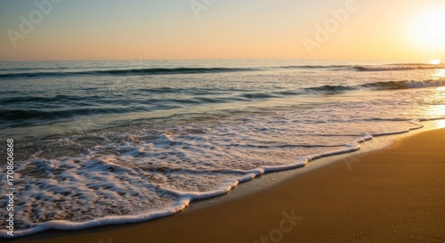 Fototapeta Naklejka Na Ścianę i Meble -  Golden sunset over a tranquil beach. Soft waves gently kiss the shore