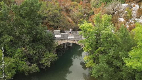 Hiker contemplating autumn on a bridge over a calm river