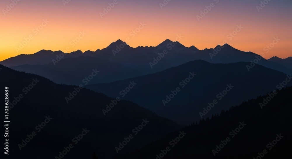 Fototapeta premium Mountain range silhouetted against a vibrant sunrise