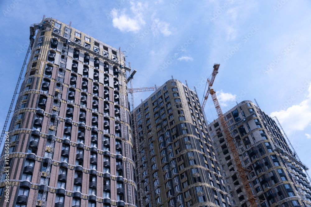 Naklejka premium New urban buildings rise against a clear blue sky in the city